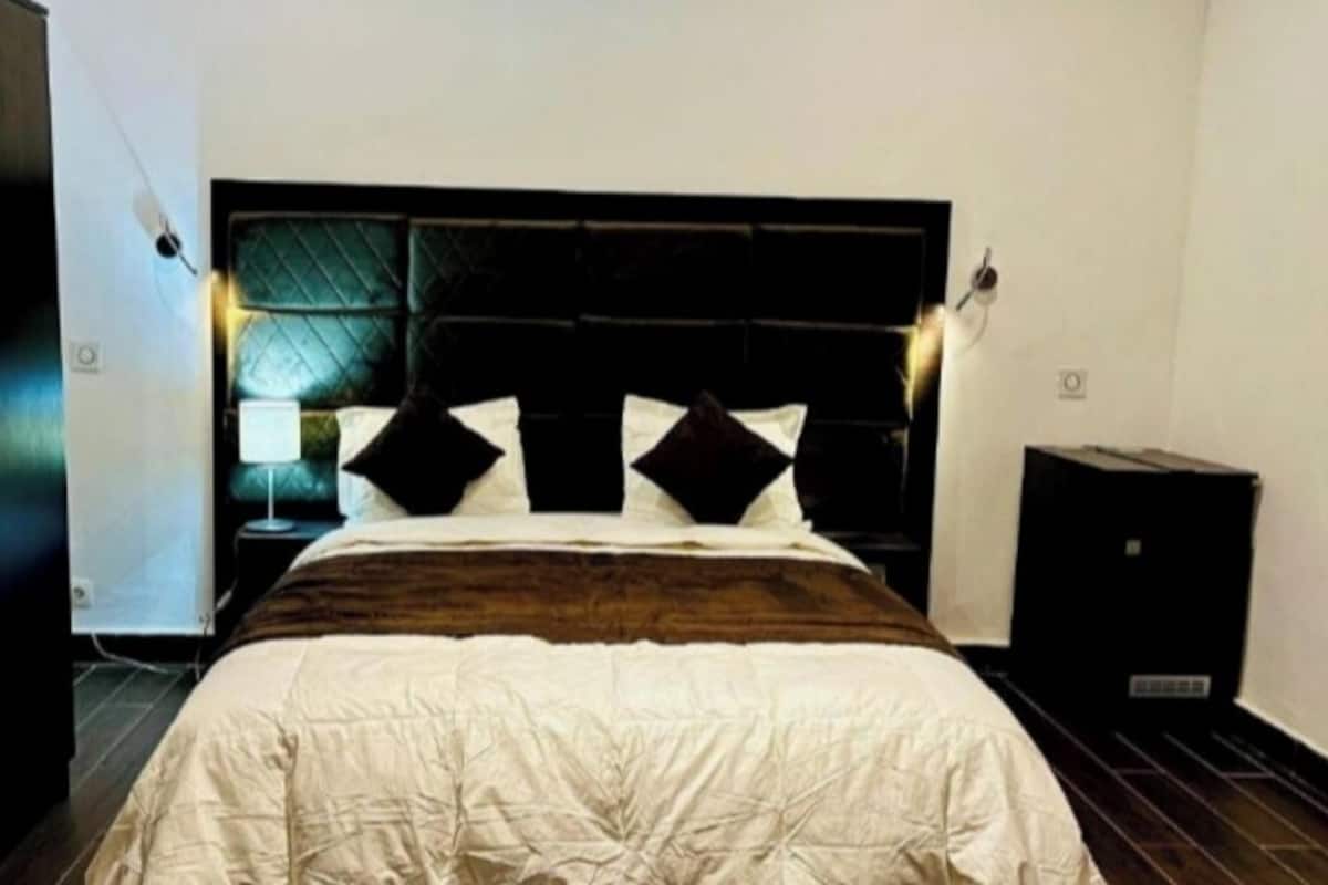Ein Schlafzimmer mit einem Bett, einem dunklen Kopfteil und einem Nachttisch.