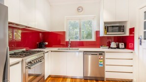 A modern kitchen with white cabinets, a stainless steel stove, a dishwasher, and a microwave.