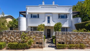 A two-story house with a stone facade, a central entrance, and a clear sky.