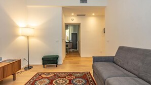 Ein modernes Wohnzimmer mit einer Couch, einer Lampe, einem kleinen Tisch und einem gemusterten Teppich.