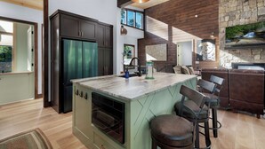 A modern kitchen with a central island, dark cabinets, and a stone accent wall.