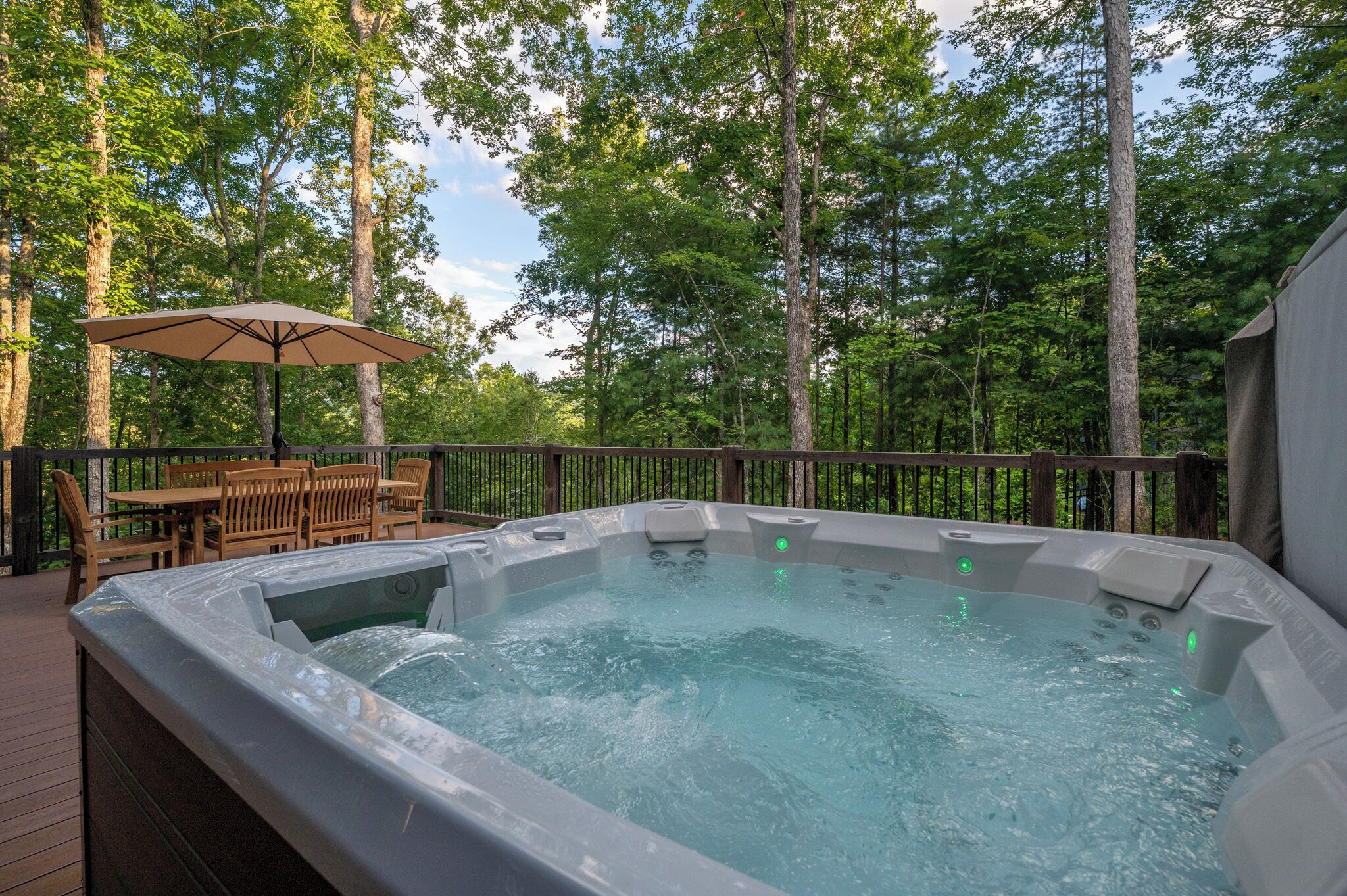 A hot tub on a wooden deck surrounded by trees.