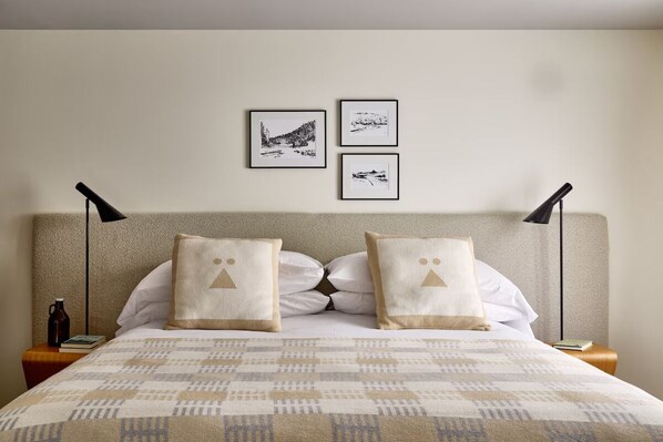 Ein ordentlich bezogenes Bett mit einer gemusterten Tagesdecke, zwei passende Kissen und drei gerahmte Bilder an der Wand darüber.