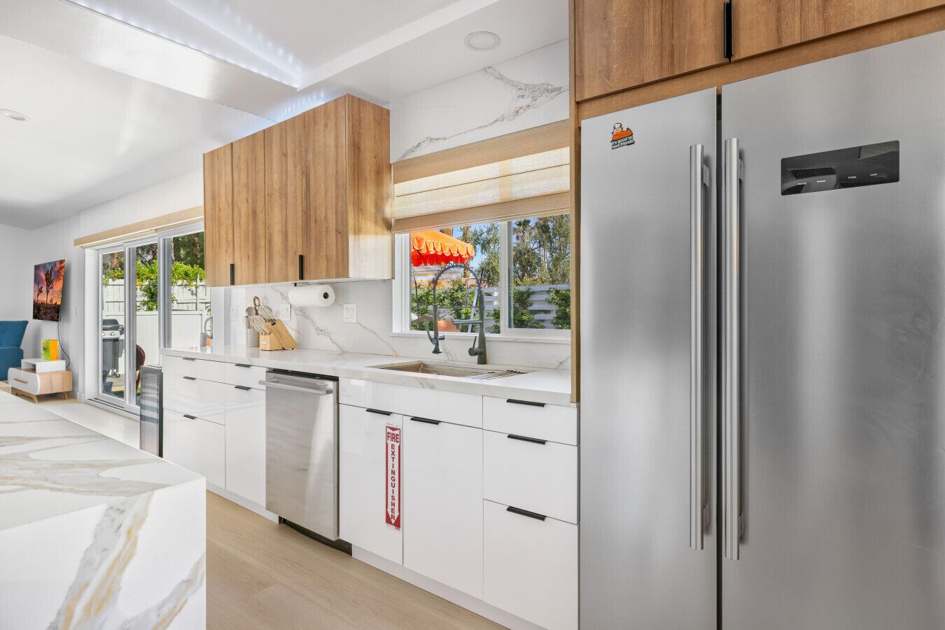 A modern kitchen with white cabinetry, stainless steel appliances, and a wooden ceiling.