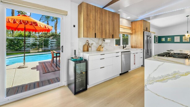 A modern kitchen with white cabinets, a built-in oven, and a large island with a stove.