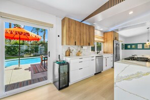 Une cuisine moderne avec des meubles blancs, un four encastré et un grand îlot central doté d’une plaque de cuisson.