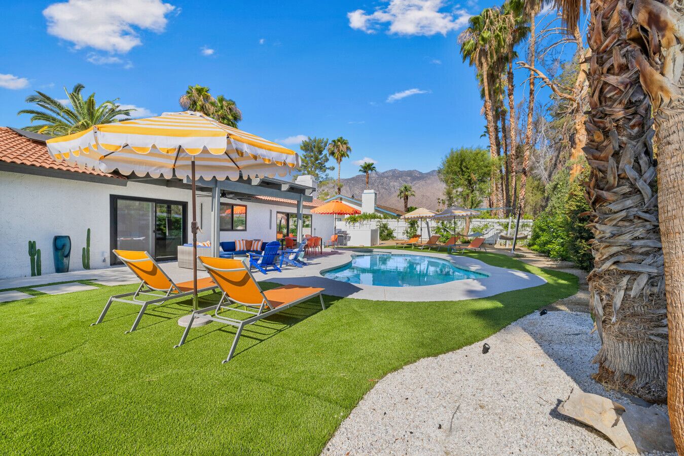 Un espace piscine extérieur moderne, doté d’une pelouse bien entretenue, de chaises longues et de parasols.