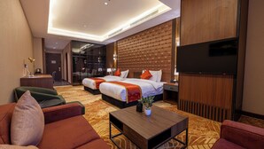 Une chambre d’hôtel avec deux lits, une télévision, une table basse et un canapé.