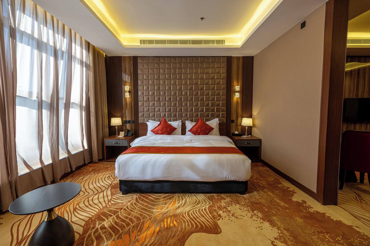 A hotel room with a large bed, a small table, and a TV.