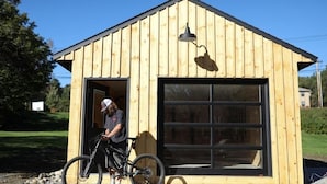 A wooden building with a large garage door, a bicycle parked in front, and a person standing near the entrance.