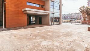 Ein modernes Gebäude mit flachem Dach, großen Fenstern und einer Beton-Terrasse.
