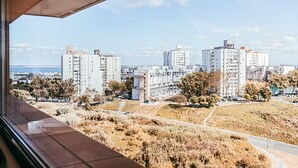 Blick auf eine Wohngegend mit hohen Gebäuden, blauem Himmel und einem Gewässer in der Ferne.