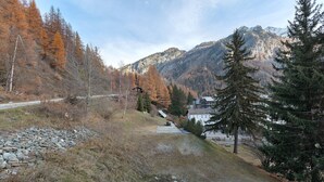 Eine gebirgige Landschaft mit einer Straße, Bäumen und einem Gebäude mit geneigtem Dach.