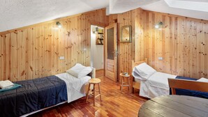 Ein Zimmer mit Holzwänden, zwei Betten, einem kleinen Hocker und einem Tisch.