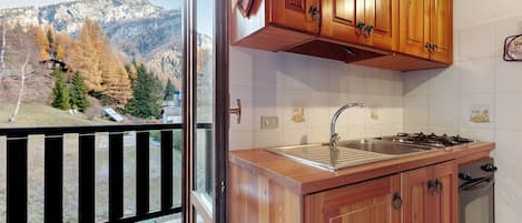 Una cocina con gabinetes de madera, un lavamanos de acero inoxidable y una estufa.