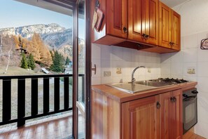 A kitchen with wooden cabinets, a stainless steel sink, and a stove.