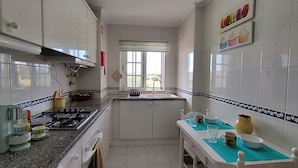 Une cuisine avec des armoires blanches, un plan de travail en granit, une fenêtre et un pare-feu en carreaux.