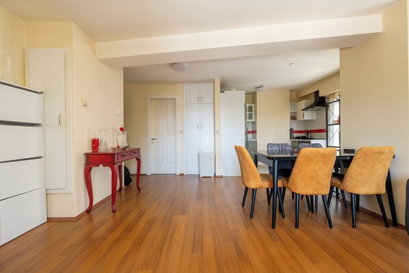 A modern kitchen with white cabinets, a red table, and a dining area with four chairs. - Charming 1-bedroom apartment with view, elevator and AC (İstanbul)
