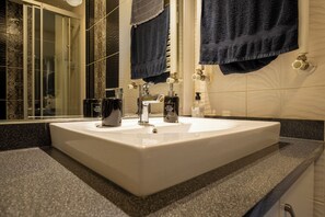 Une salle de bain avec un lavabo blanc, un miroir et deux serviettes accrochées au mur.
