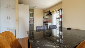 A modern kitchen with white cabinets, a black marble dining table, and two chairs.