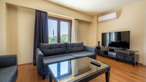A modern living room with a sectional sofa, a flat-screen TV, and a glass coffee table.