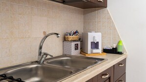Cozinha com pia dupla, máquina de café e pequeno balcão com cesta e xícaras.