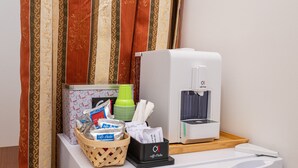 A hotel room with a coffee machine, a basket of snacks, and a stack of plates. - Room 'Sole' with Private Terrace, Wi-Fi and Air Conditioning (Santa Cesarea Terme)