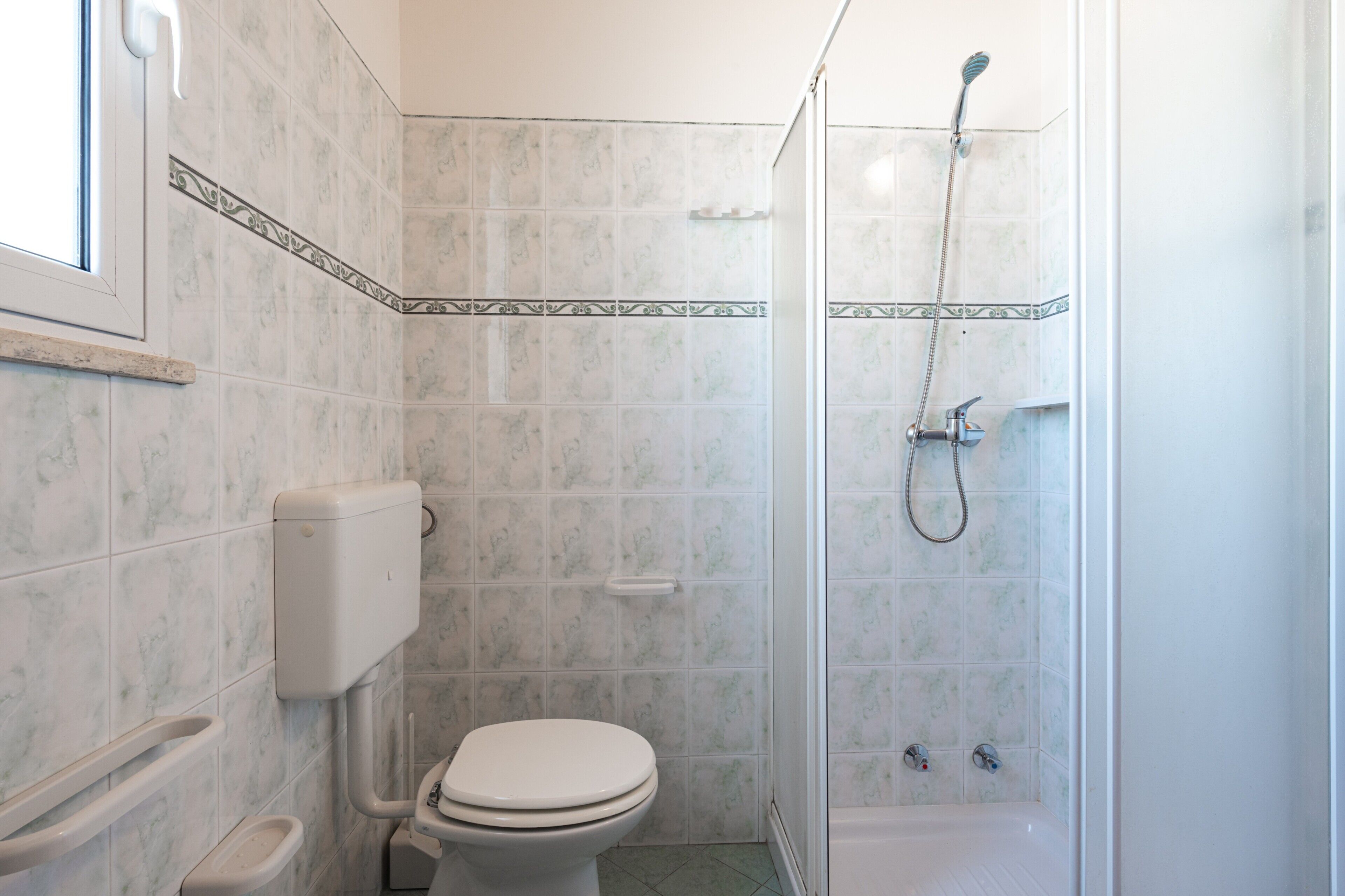 Un bagno con il WC, una doccia e una finestra.