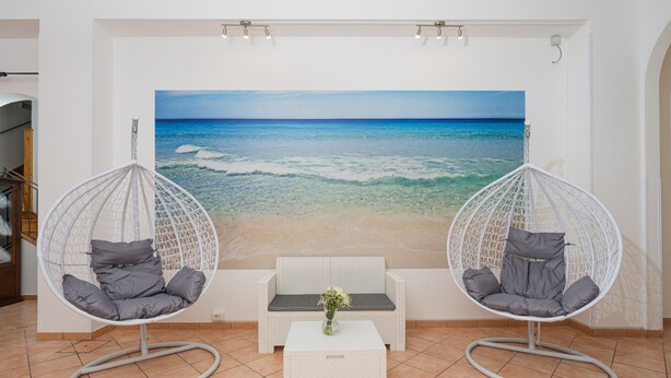 A room with a beach mural, two hanging chairs, a sofa, and a coffee table. - 'Angeli Nel Salento - Room 7' with Private Terrace, Wi-Fi, and Air Conditioning (Cocumola)