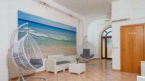A modern room with a beach mural, white wicker furniture, and a private door.