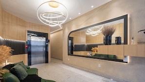 A modern lobby with a green sofa, a large mirror, and a ceiling light fixture. - 450m Beach Apt - Bbq, 3 Suites Tah0602 (Itapema)