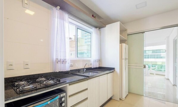 Una cocina moderna con estufa a gas, pileta y refrigerador.