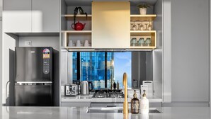 Eine moderne Küche mit einem eingebauten Kühlschrank, einer Kaffeemaschine und Blick auf eine Stadtlandschaft durch große Fenster.