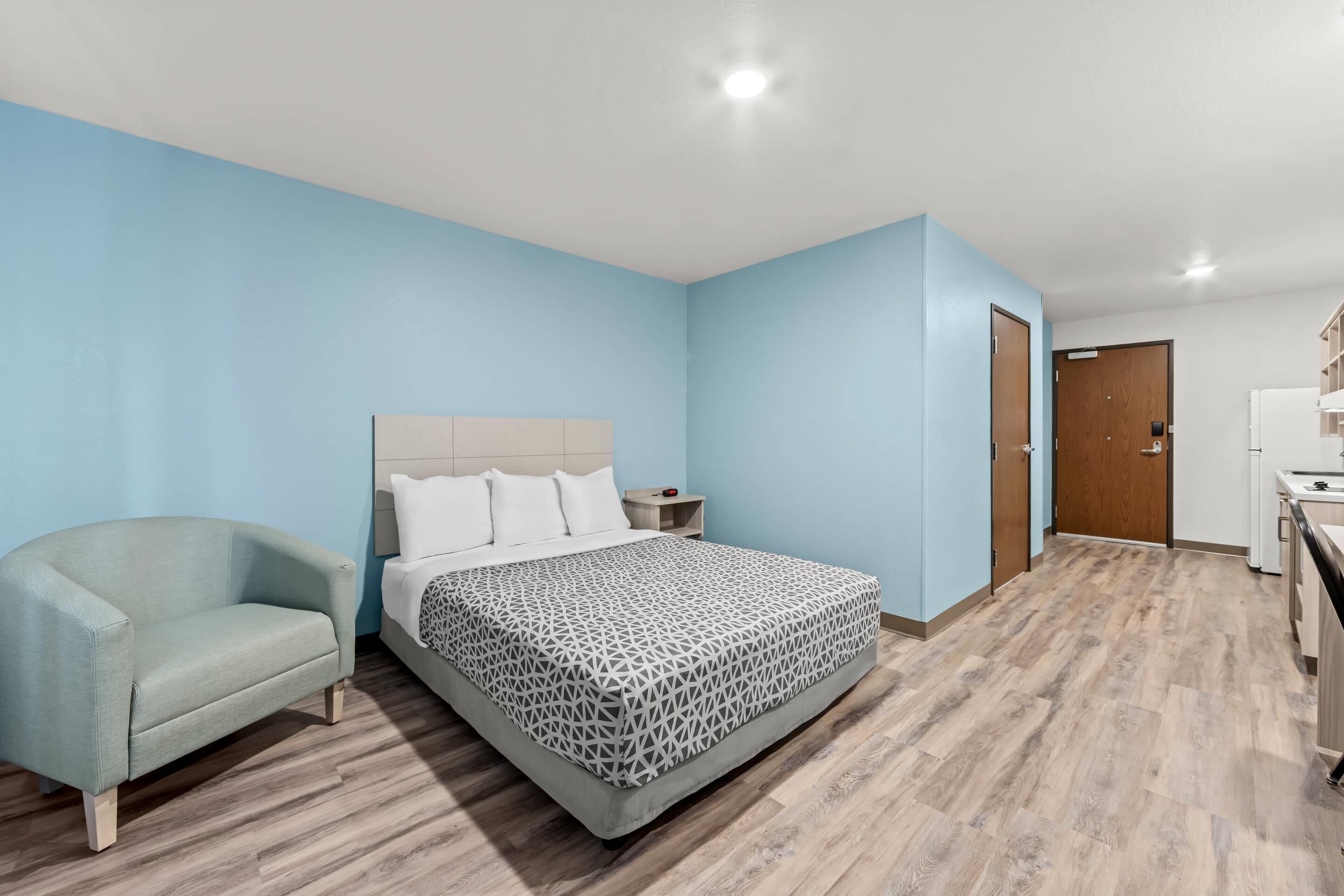 Une chambre à coucher avec un lit, une chaise, une table de chevet et un plancher en bois.