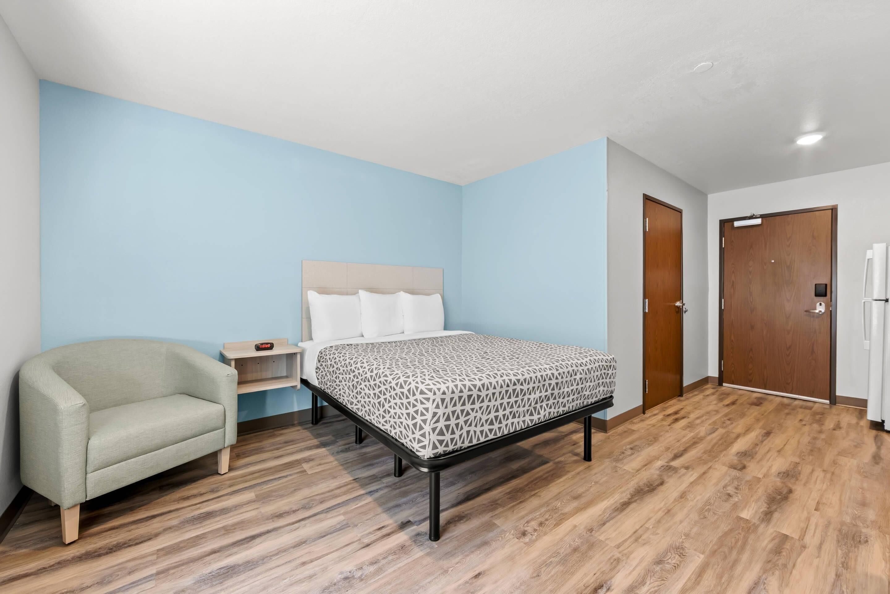 A bedroom with a bed, a chair, a nightstand, and a wardrobe.
