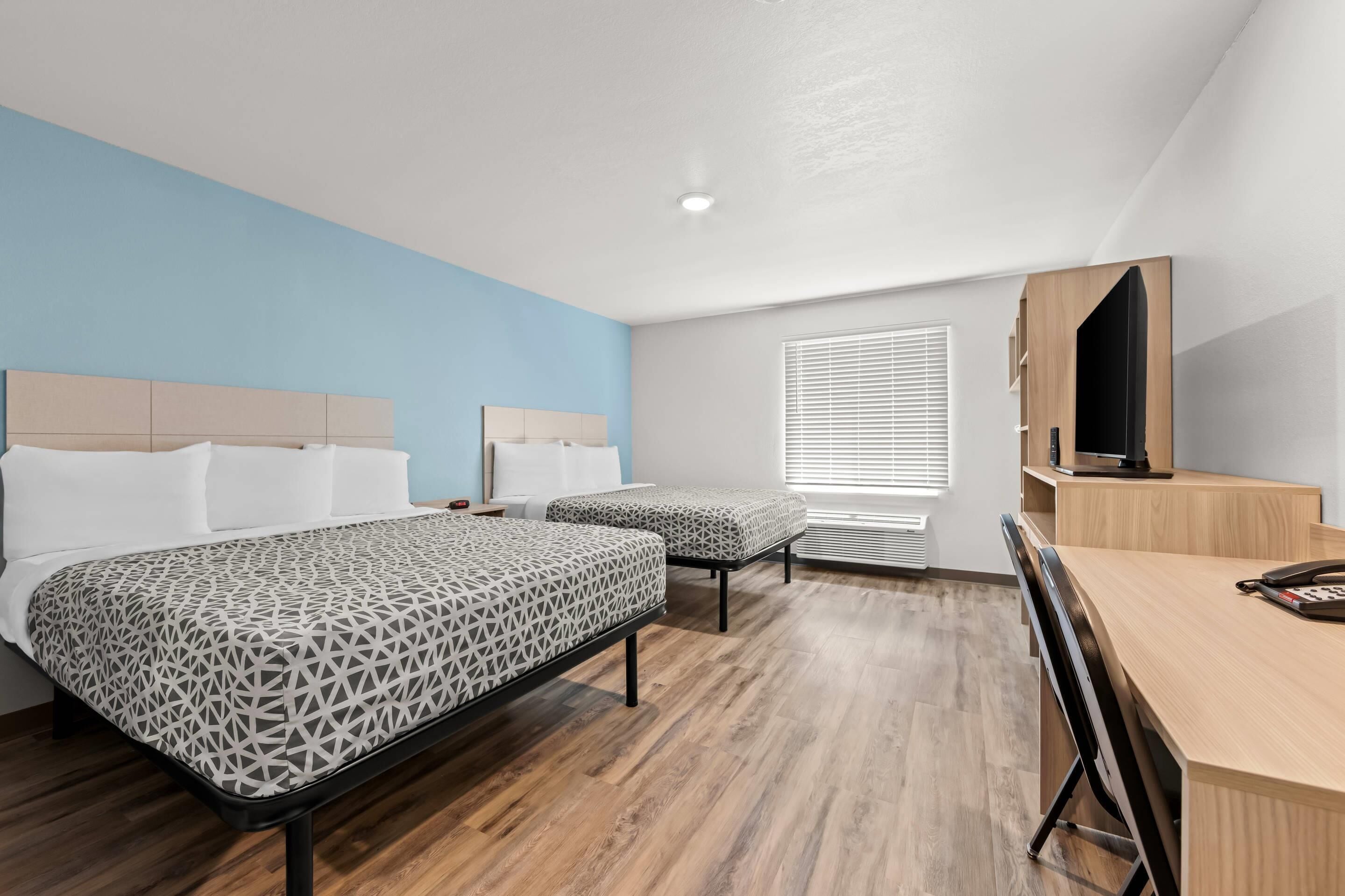 Una habitación de hotel moderna con dos camas, un escritorio y una televisión.