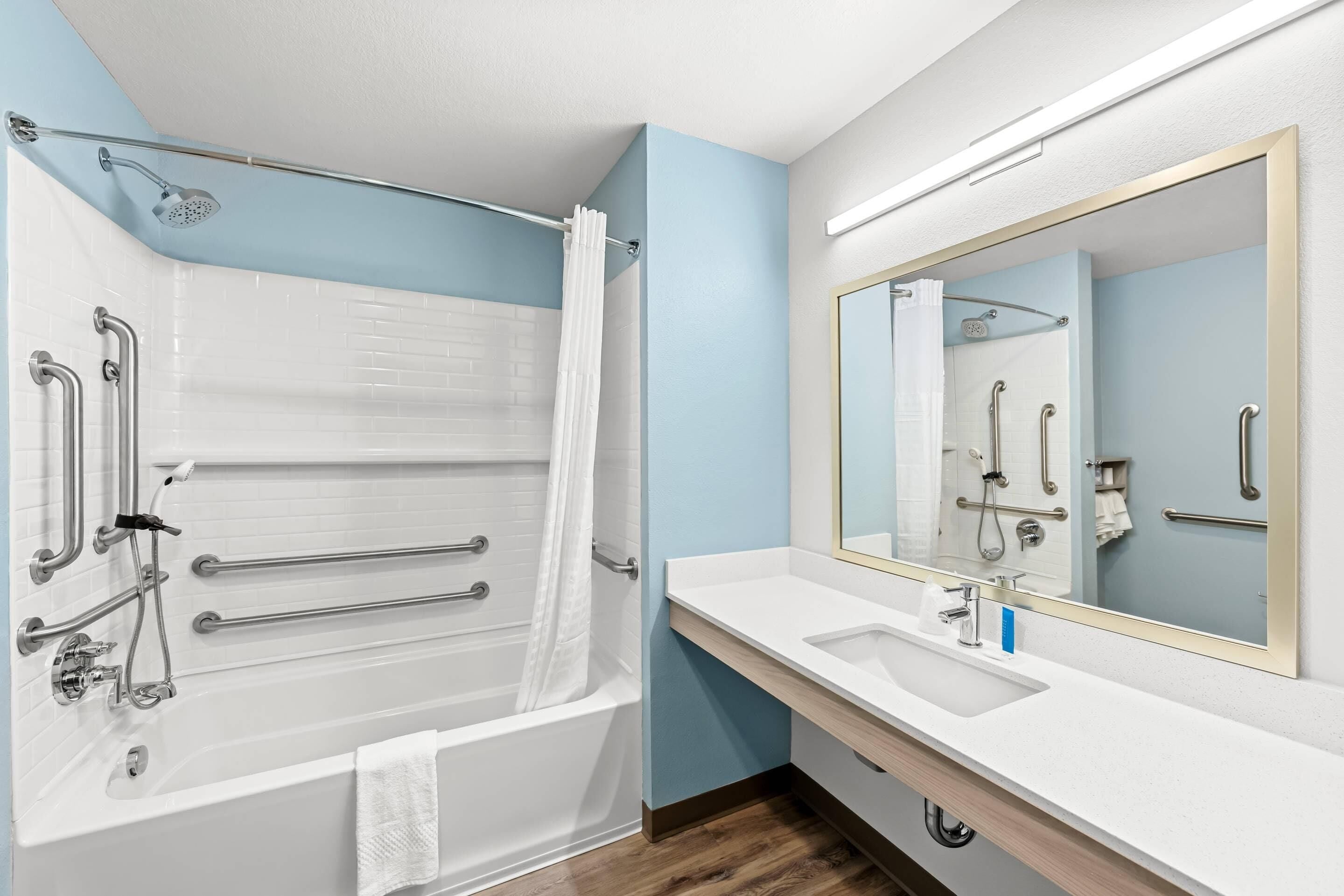 A modern bathroom with a bathtub, shower, and vanity.