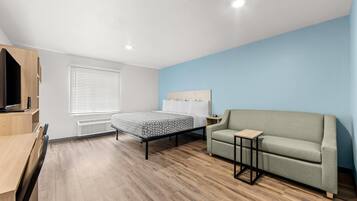 Un dormitorio moderno con una cama, un sofá, un televisor y un escritorio.