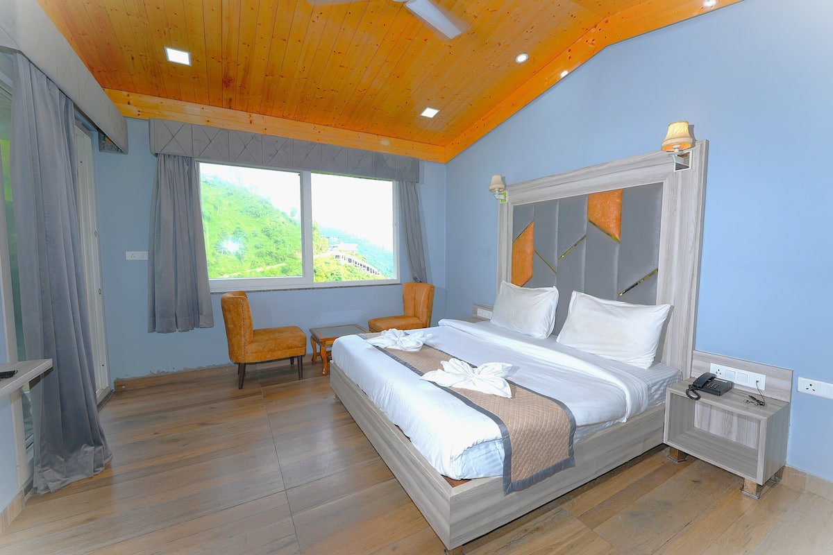 Un dormitorio con una cama grande, una silla, una mesita de noche y una ventana con cortinas.