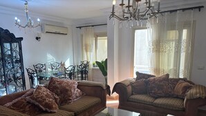 A living room with two brown sofas, a glass coffee table, and a chandelier.