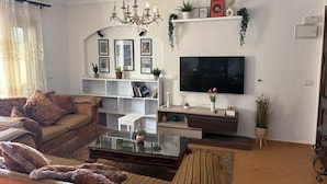 A living room with a sofa, a glass coffee table, a TV, and a bookshelf.