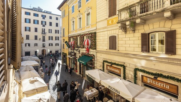 A narrow street with outdoor seating at a pizzeria and a restaurant, surrounded by historic buildings with balconies and shutters. - Rental in Rome Pantheon Apartment (Rome)