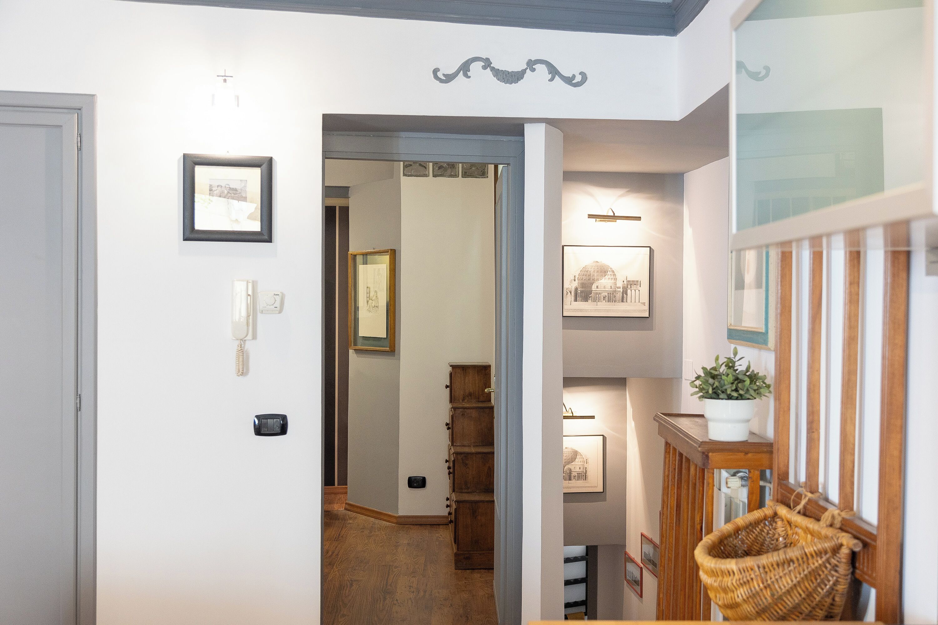 A hallway with a wooden floor, a door, and a wall-mounted telephone.