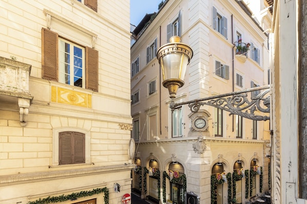 A narrow street with buildings featuring traditional architecture, including a street lamp and decorative garlands. - Rental in Rome Pantheon Apartment (Rome)