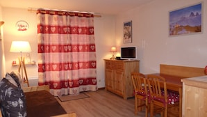 A cozy room with a wooden desk, two chairs, a bed, a TV, and a painting on the wall. - Mountain Apartment in Saint-sorlin (Saint-Sorlin-d'Arves)
