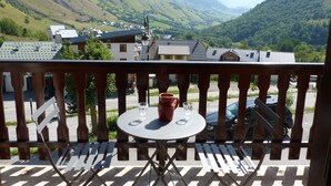 A balcony with a table and chairs, overlooking a valley with houses and mountains. - Mountain Apartment in Saint-sorlin (Saint-Sorlin-d'Arves)