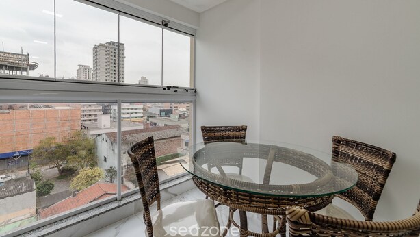 A balcony with a glass table and wicker chairs, overlooking a cityscape. - 2BR apt w/ BBQ 700m From the Beach Sir0501 (Itapema)