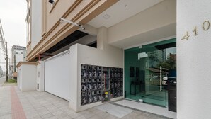 A building entrance with a glass door, a security camera, and a wall-mounted electrical panel. - 2BR apt w/ BBQ 700m From the Beach Sir0501 (Itapema)
