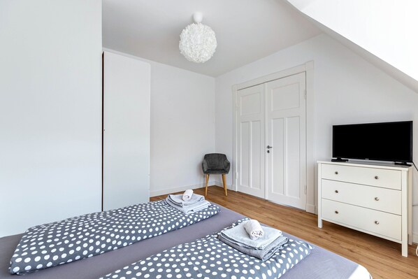 Un dormitorio con dos camas, televisión, cómoda y una silla.