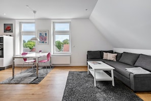 Un espacio moderno con comedor, sofá y vistas al exterior.